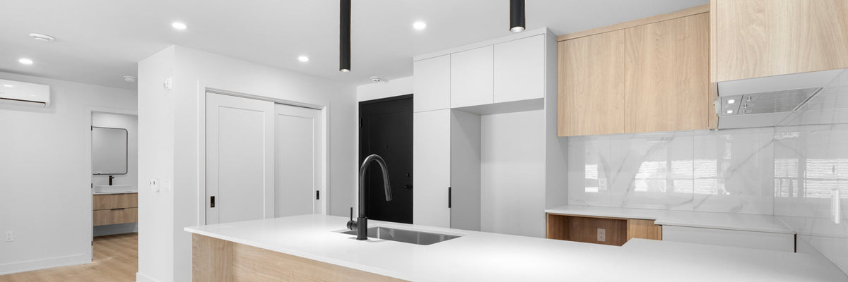 Modern residential lighting supplies featuring three matte black cylindrical pendant lights over a white kitchen island.