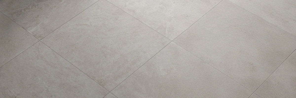 Commercial flooring supplies showcasing large-format matte grey porcelain or ceramic floor tiles in a minimalist interior setting.