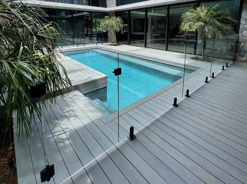 Commercial and residential architectural railing supplies featuring a frameless glass pool fence system with black spigots